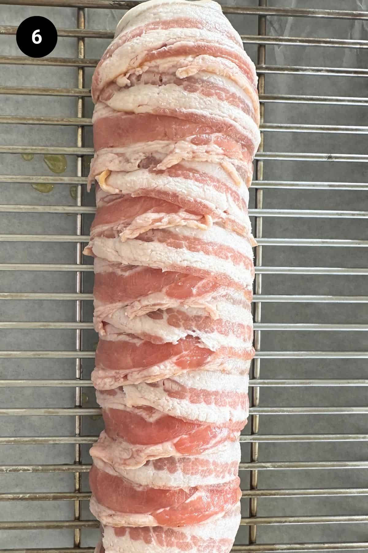 Stuffed and bacon wrapped lamb leg on a roasting tray.