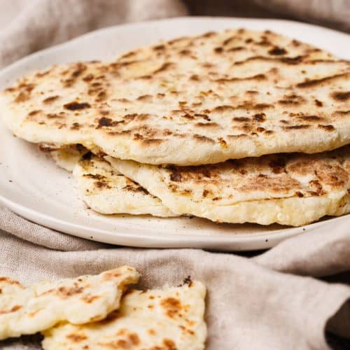 Flatbreads on a plate wrapped in a tea towel.