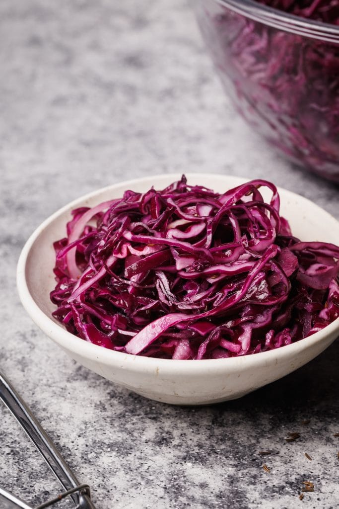 Red cabbage salad in a white bowl.