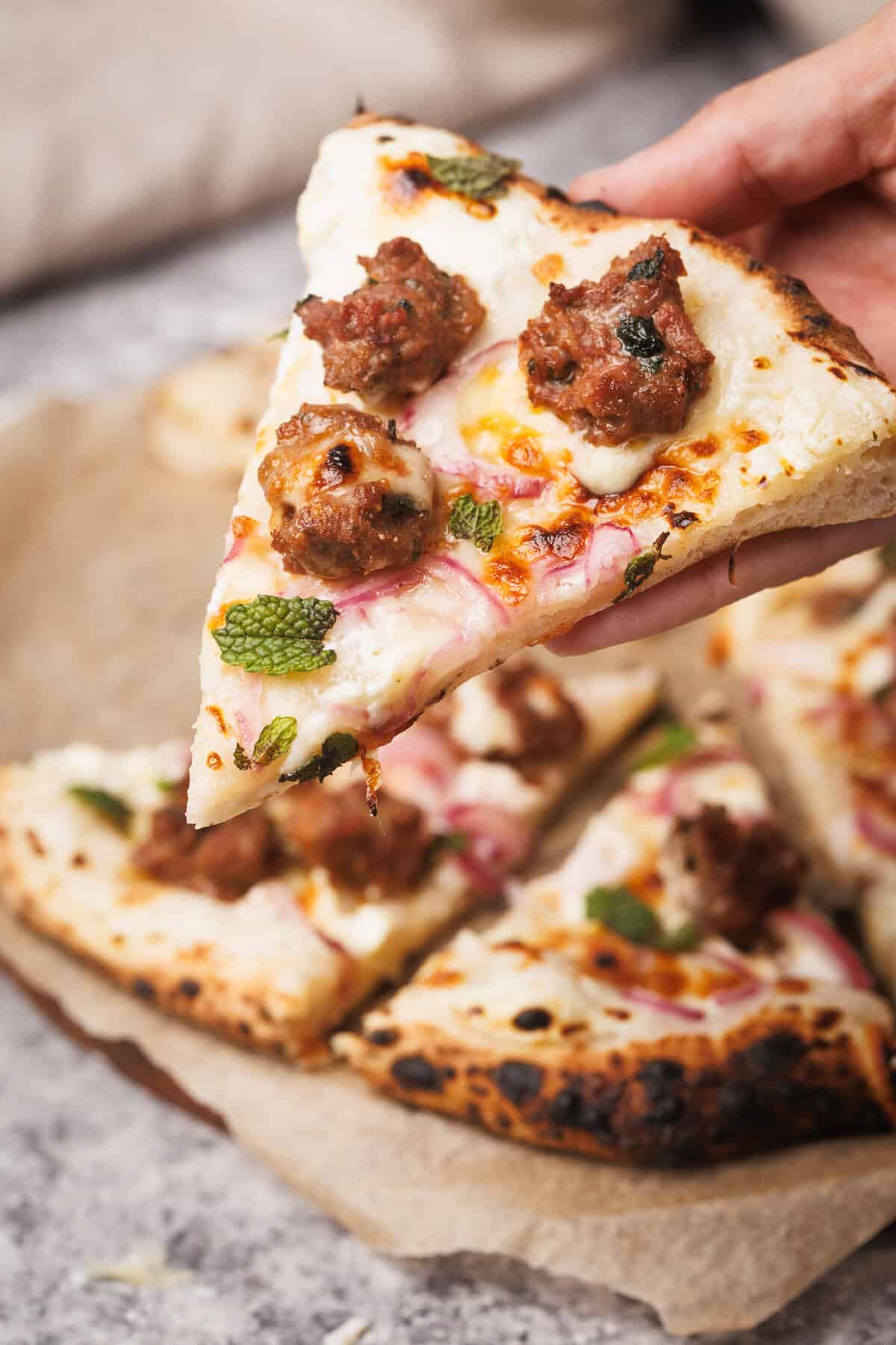 A slice of German pizza being lifted.