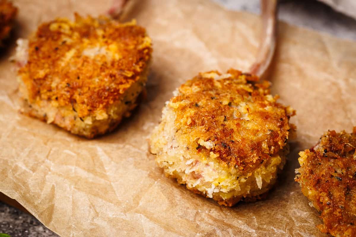 Crumbed lamb chops on some brown baking paper.