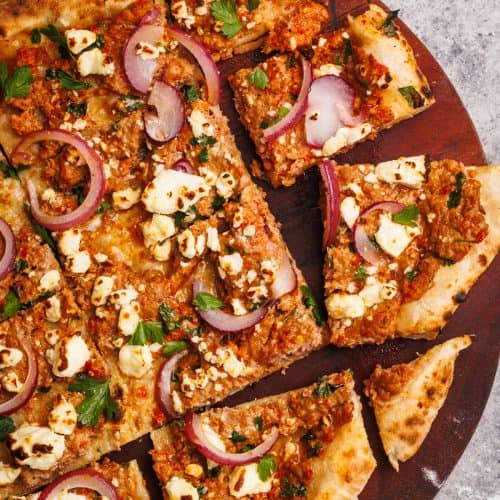 Sliced up Turkish pizza on a wooden board.