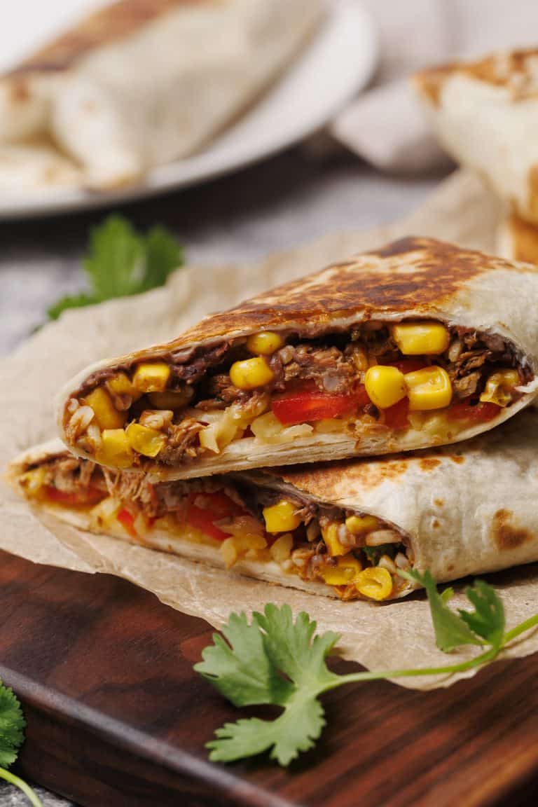 Birria burrito cut in half on a wooden board.