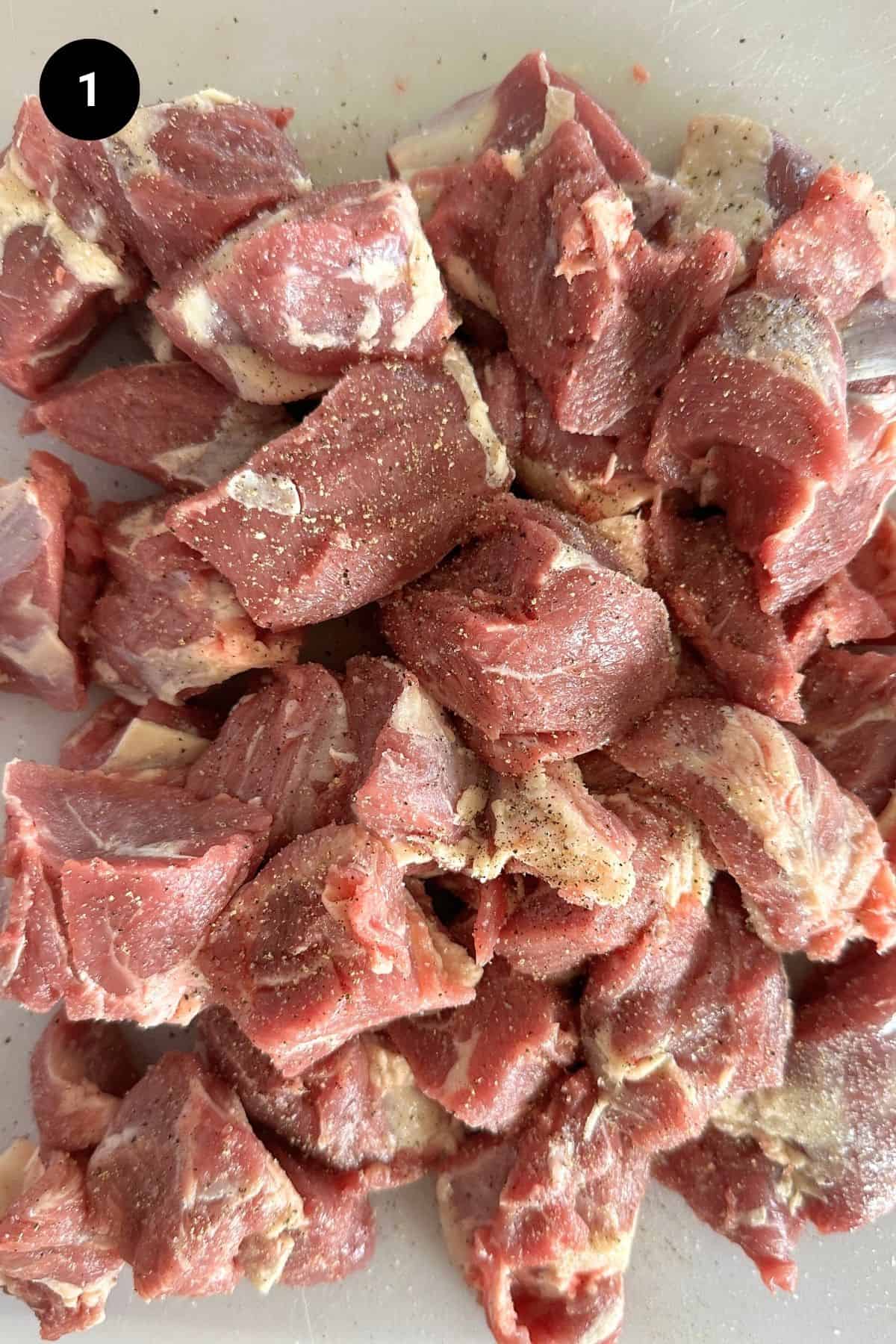 Seasoned raw lamb pieces on a chopping board.