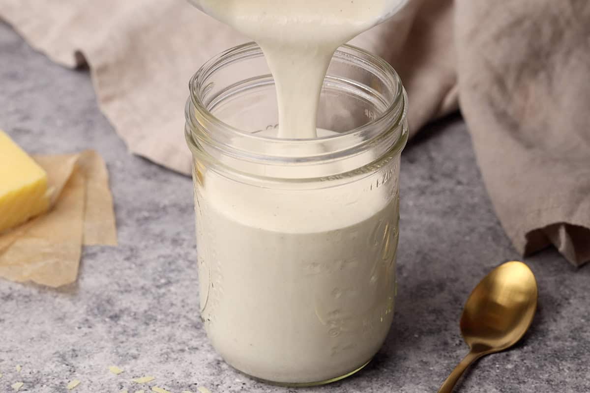 Cottage cheese Alfredo sauce being poured into a mason jar.