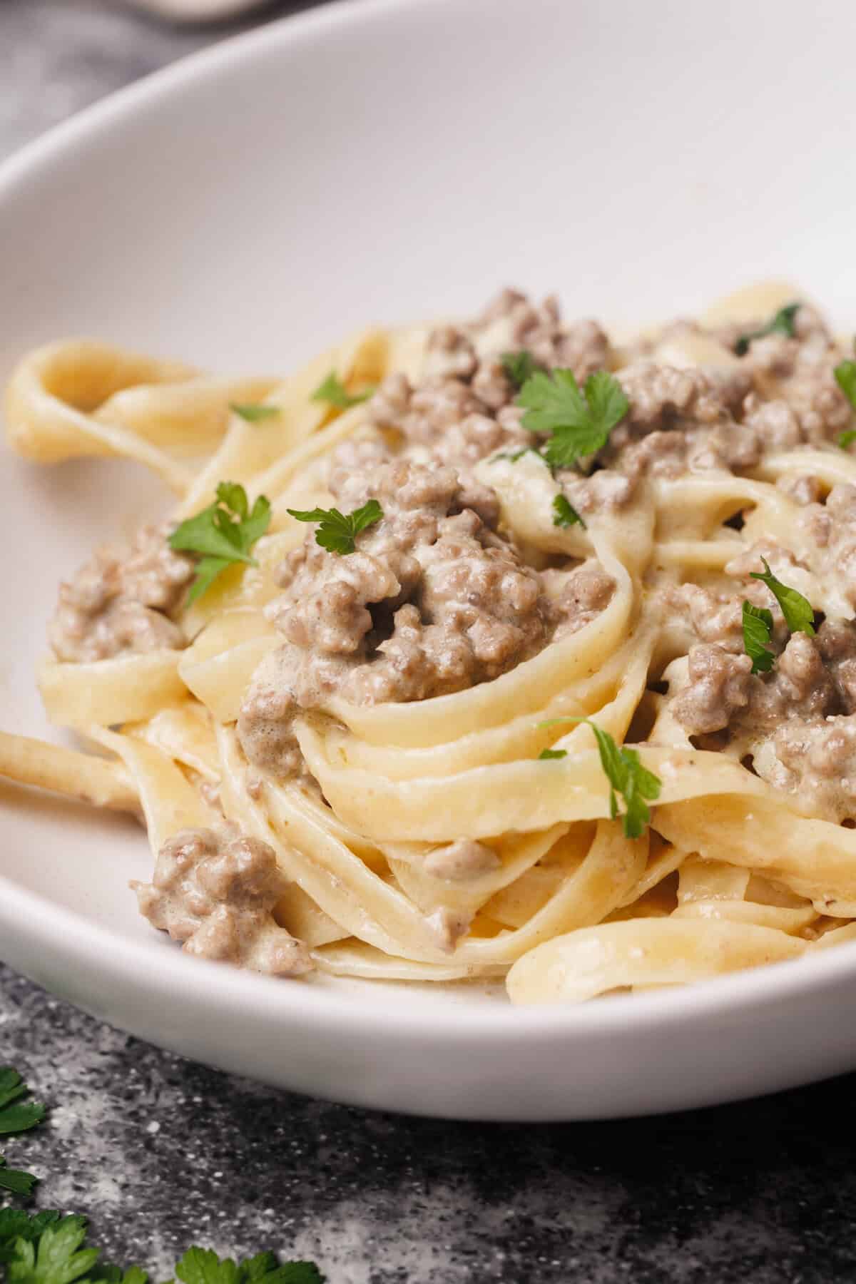 Hamburger Alfredo pasta in white bowl.