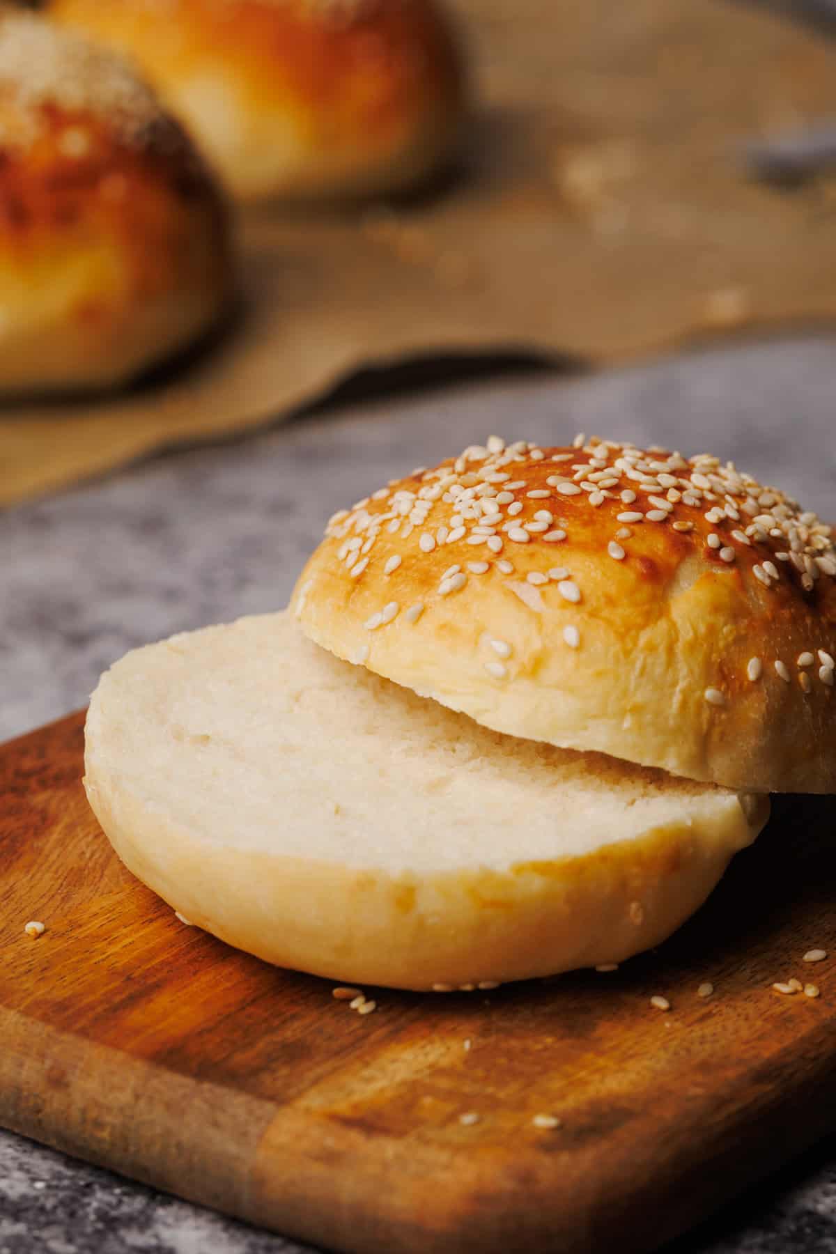 Hamburger bun cut in half on a wooden board.