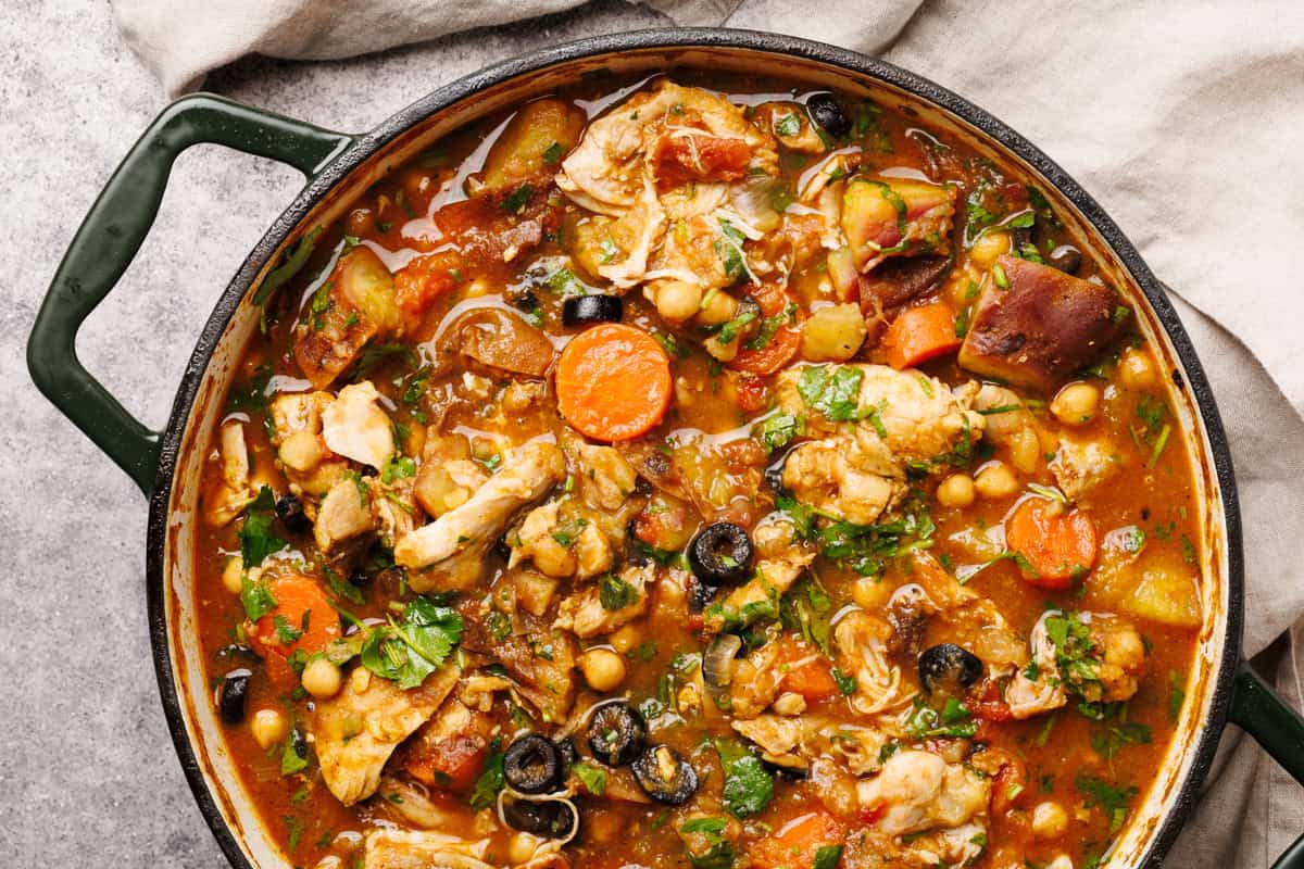 Moroccan chicken stew in a large Dutch oven next to a linen tea towel.
