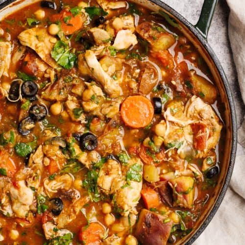 Moroccan chicken stew in a large Dutch oven next to a linen tea towel.
