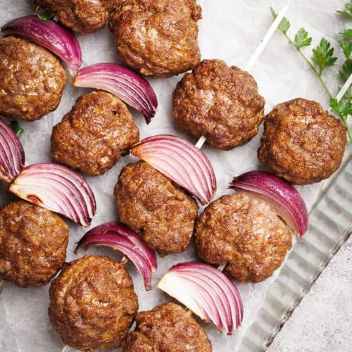 Cooked meatball skewers on a metal plate.