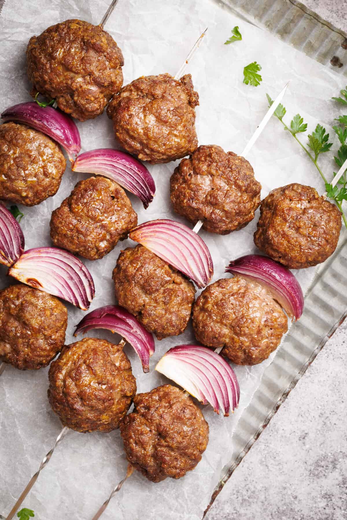 Cooked meatball skewers on a metal plate.