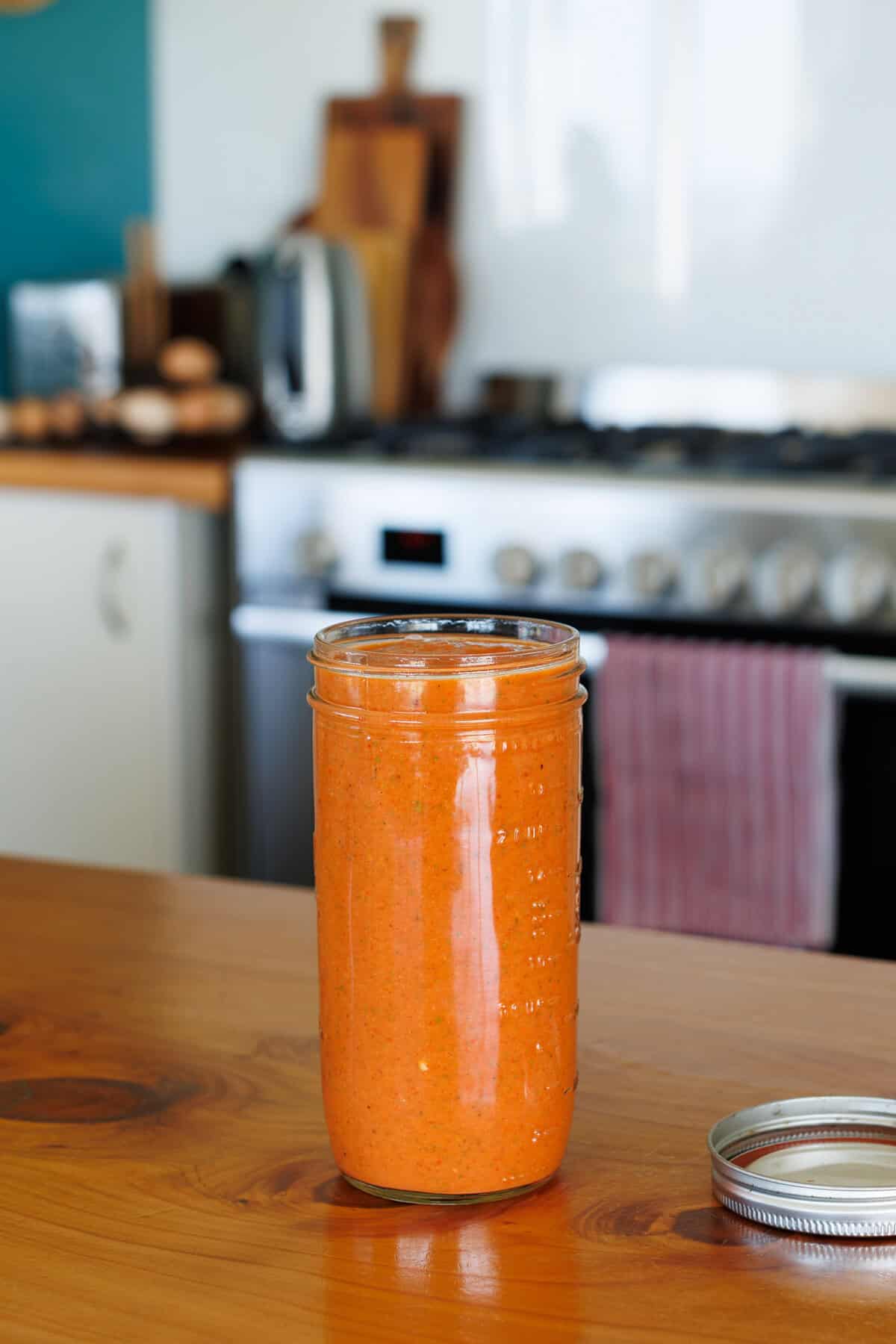 Romesco sauce in a mason jar on a wooden kitchen bench.