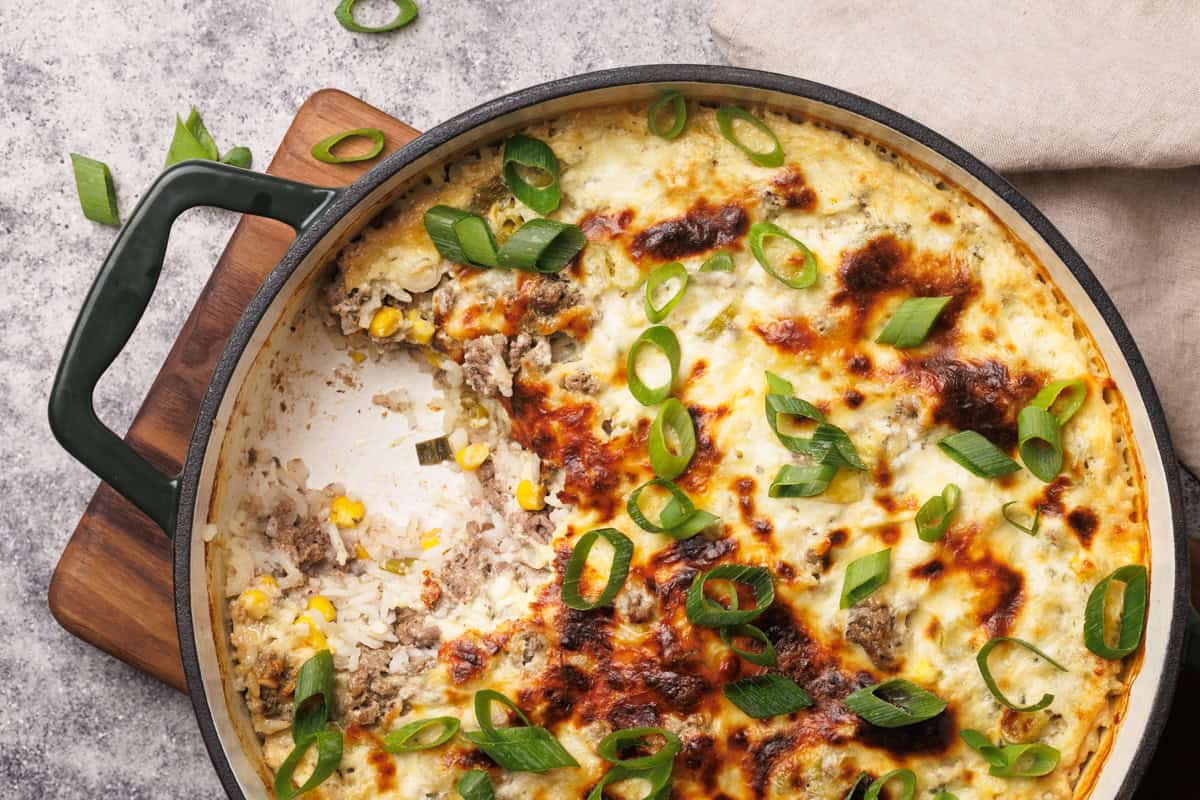 Casserole dish on a wooden board, top down view, one serving taken out of it.