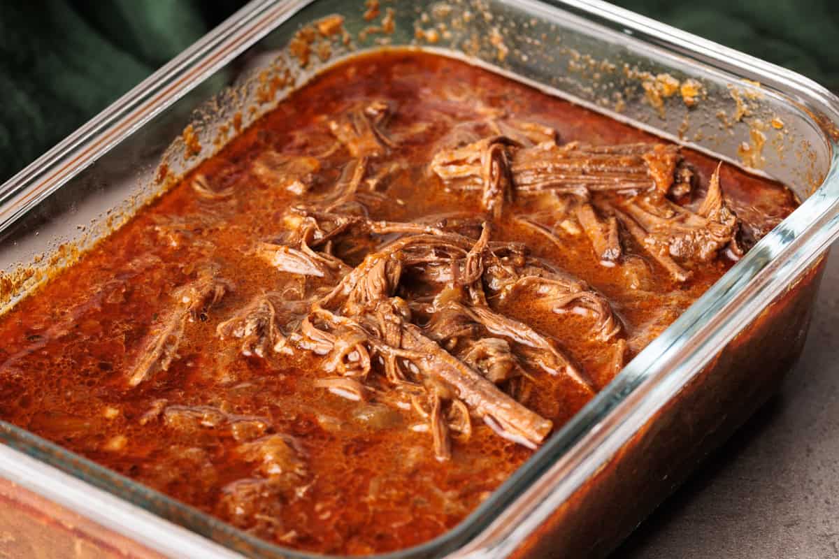 Beef barbacoa in a glass container.