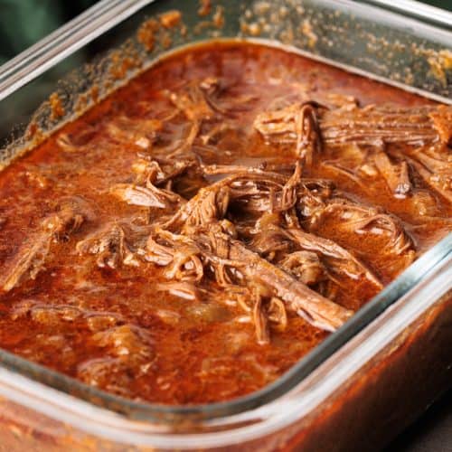 Beef barbacoa in a glass container.