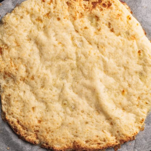 Cottage cheese pizza crust on parchment paper.