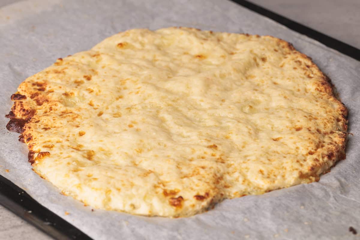 Cottage cheese pizza crust on parchment paper.