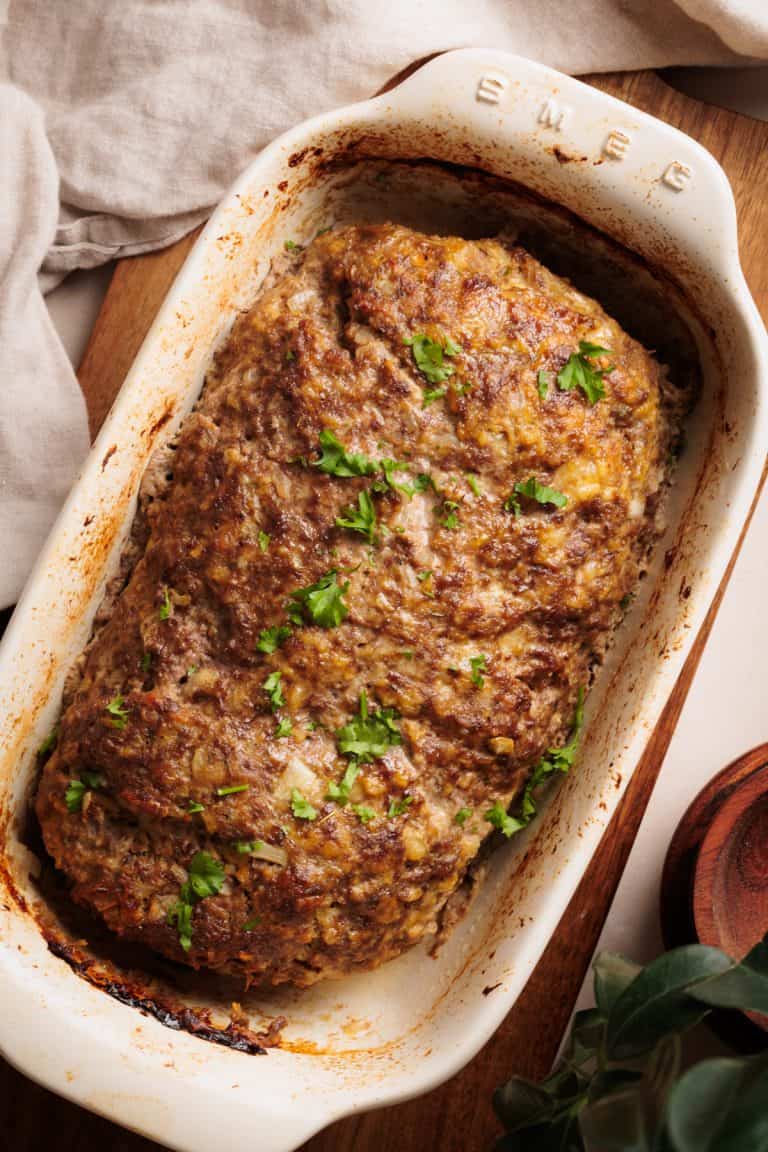 Cottage Cheese Meatloaf in a ceramic loaf pan on a wooden board.