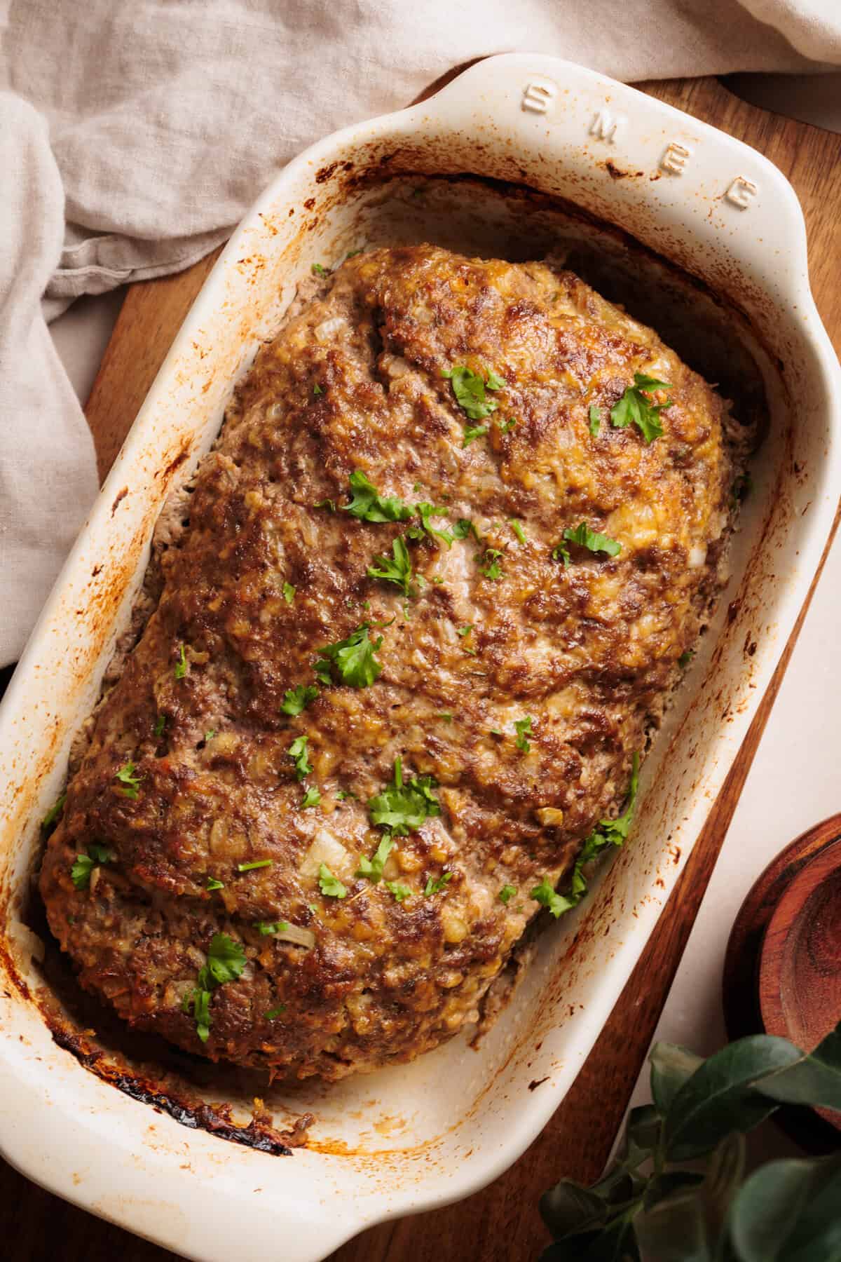 Cottage Cheese Meatloaf in a ceramic loaf pan on a wooden board.