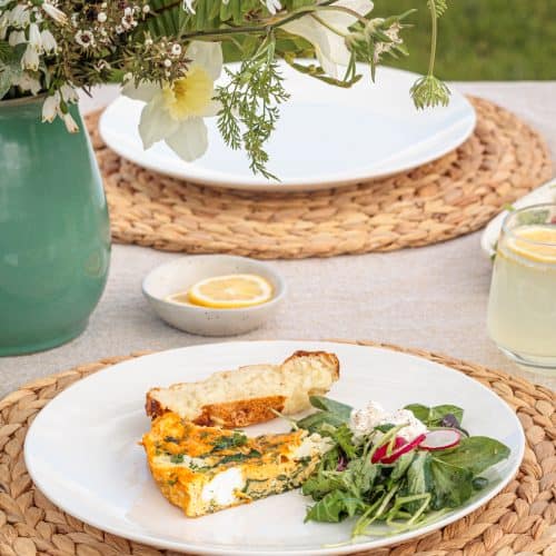 Garden Frittata with Cottage Cheese on a white plate next to bread and salad.