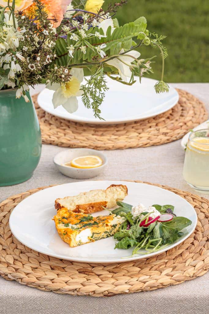 Garden Frittata with Cottage Cheese on a white plate next to bread and salad.
