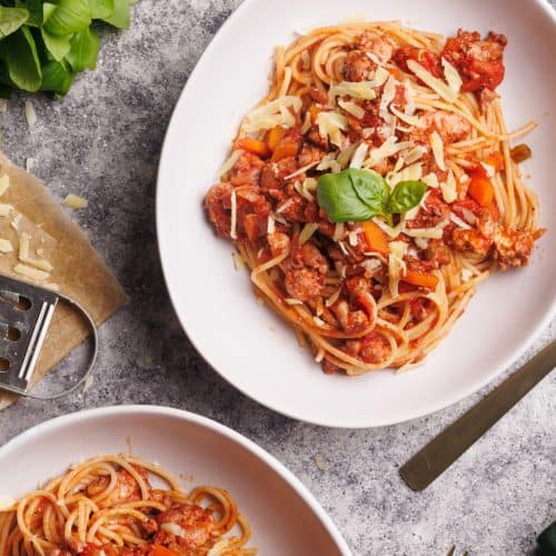 Two plates with chicken spaghetti bolognese.