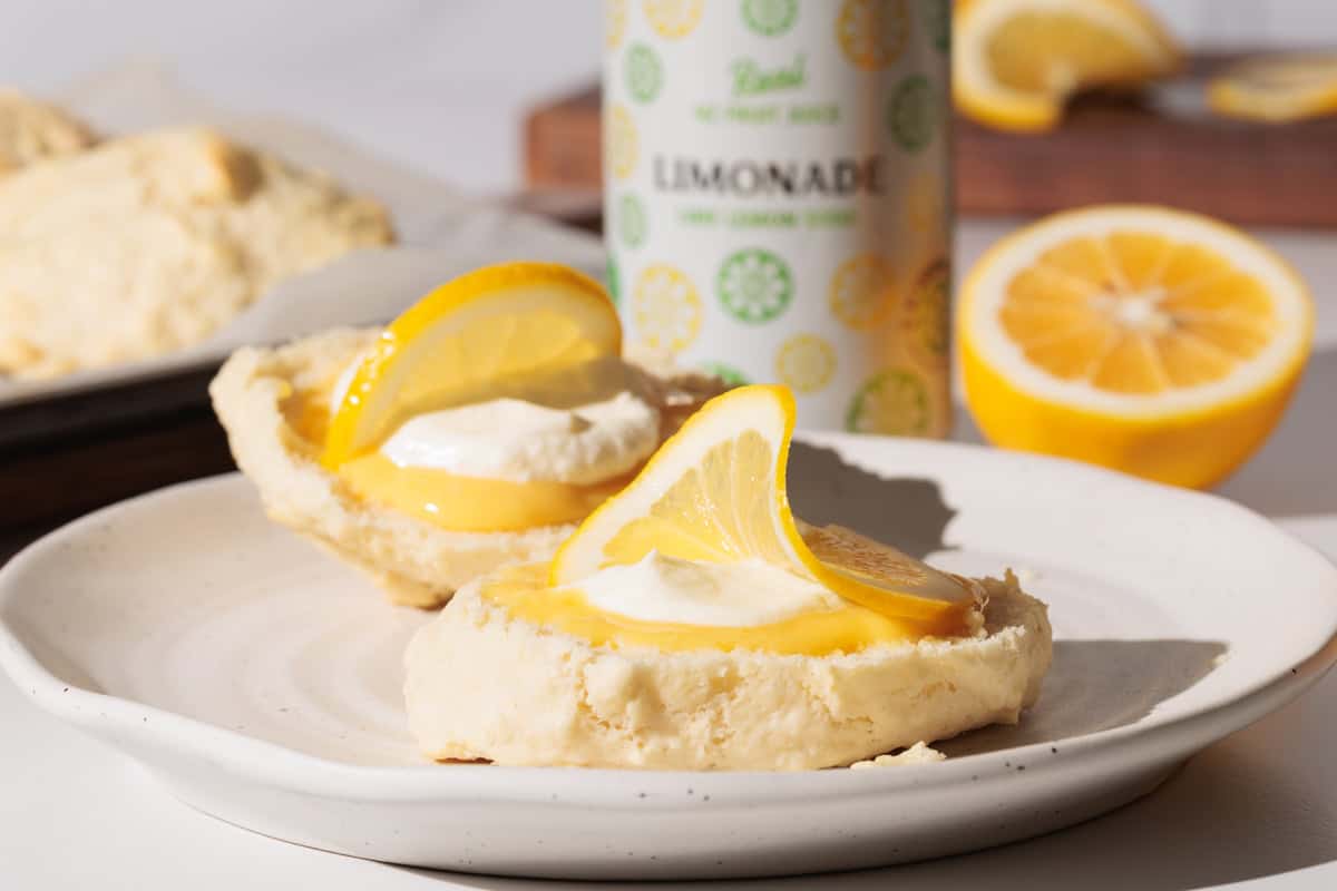 Lemonade scone with lemon curd and cream on a white plate.
