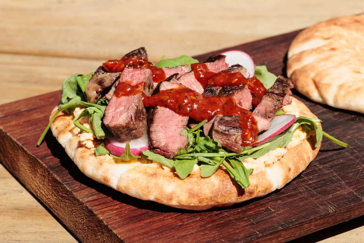 Steak flatbread on a wooden board.