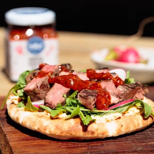 Steak flatbread on a wooden board.