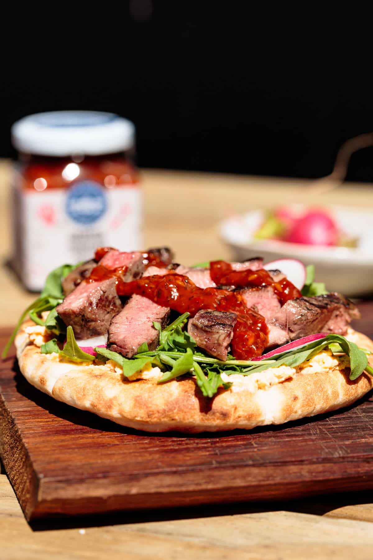 Steak flatbread on a wooden board.
